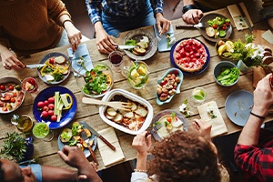 Birds’-eye view of group of people sitting at wooden table with several healthy dishes
