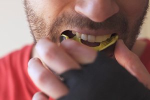 Man in red shirt removing yellow mouthguard