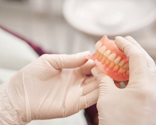 Dentist carefully holding a denture