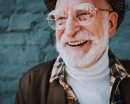 Stylish man smiling on blue-brick background