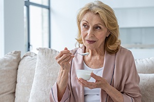A woman eating soft food after dental implant surgery