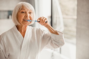 A woman brushing her teeth after dental implant surgery