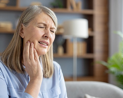 Older woman rubbing her jaw in pain