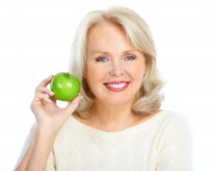 older woman smiling holding apple